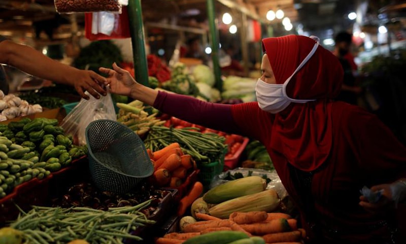 In this file photo, a woman wearing a protective mask shops for vegetables at a traditional market in Jakarta, Indonesia. — Reuters/File